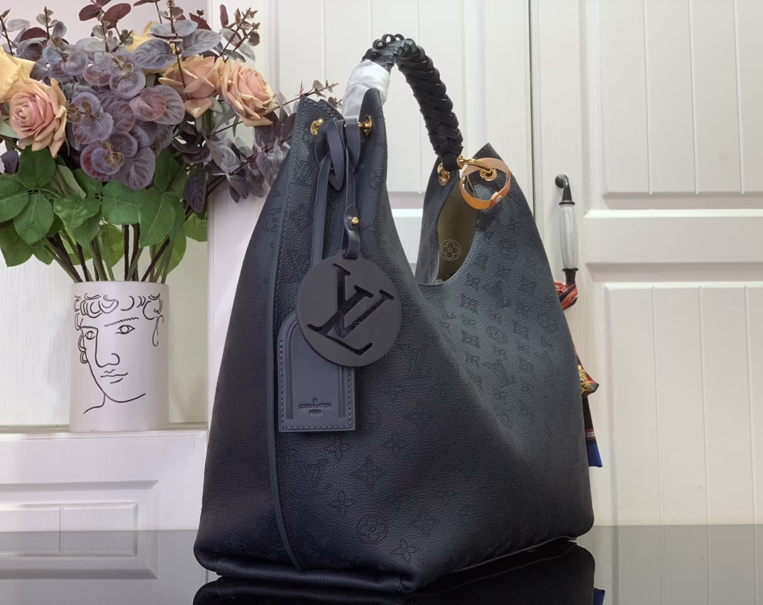 This elegant Carmel tote is crafted from Mahina calfskin leather, delicately perforated with the brand's signature monogram. Perfectly sized for everyday essentials, including a laptop, the versatile design features a removable LV braided leather charm. Note the address label, which pays homage to traditional Louis Vuitton trunks.