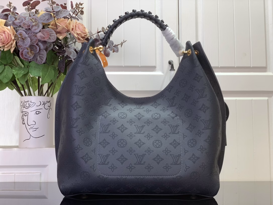 This elegant Carmel tote is crafted from Mahina calfskin leather, delicately perforated with the brand's signature monogram. Perfectly sized for everyday essentials, including a laptop, the versatile design features a removable LV braided leather charm. Note the address label, which pays homage to traditional Louis Vuitton trunks.