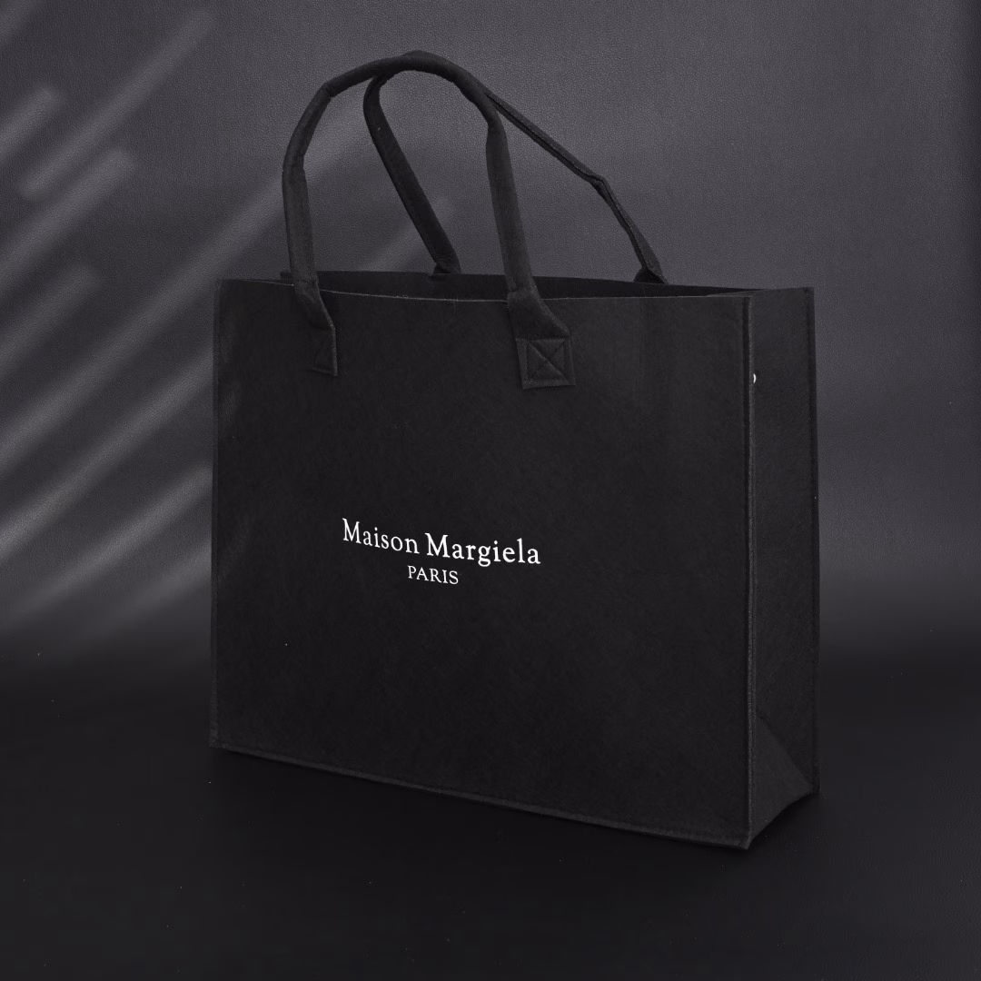 Maison Margiela MM6 Belgian Limited Edition Tote BagUsing 140g HM imported felt, one-piece singeing process, the whole bag weighs only 300g, freeing shoulders and hands. The printed film board is scraped 4 times, which contrasts strongly with the overall elegant black. Produced by a large factory, perfect details, all sizes are in stock.