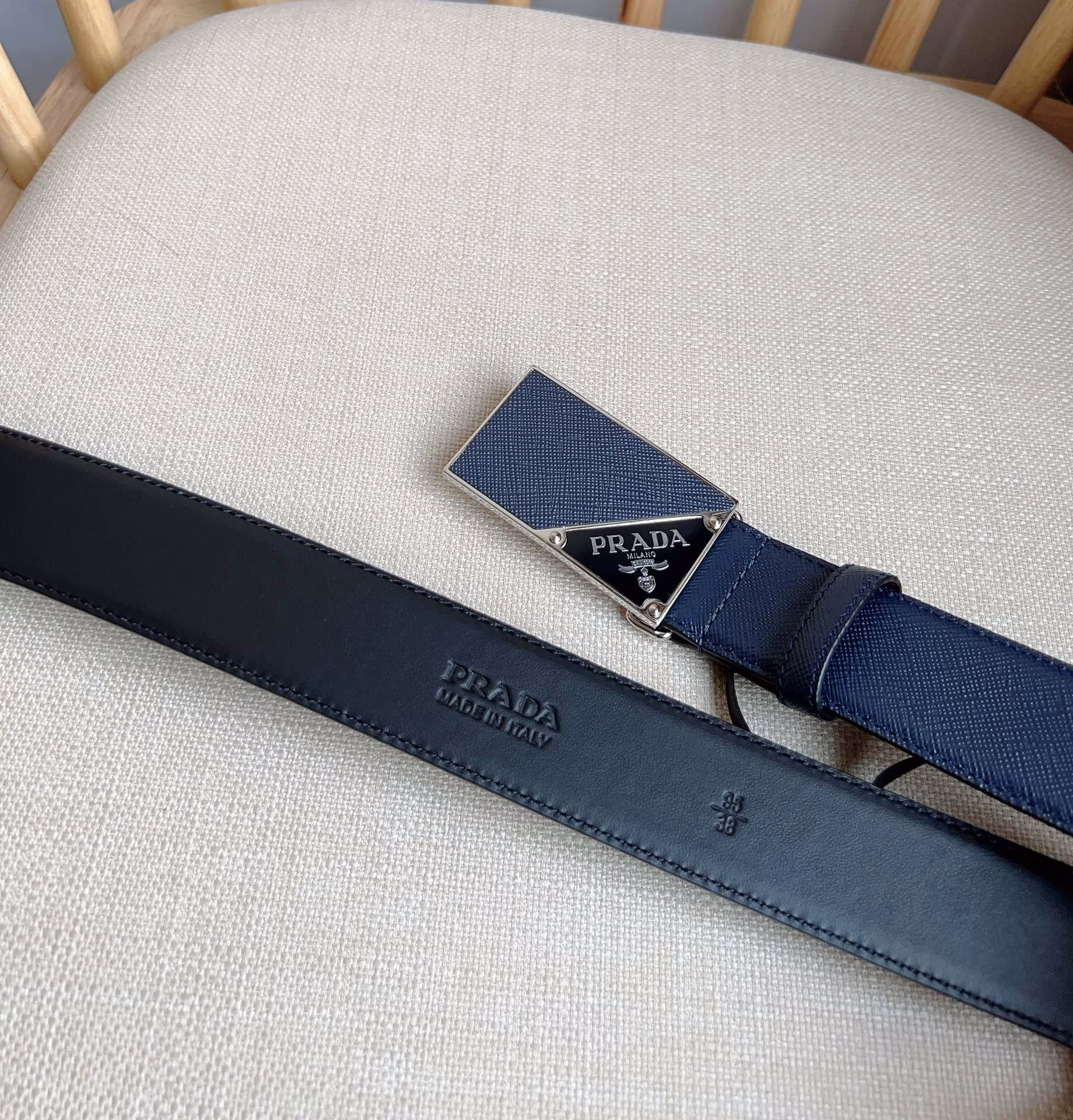 The latest model from PRADA This versatile accessory features a simple yet sophisticated design The elegant Saffano leather with cross-line texture adds a subtle touch The iconic metal lettering logo embellishes the buckle