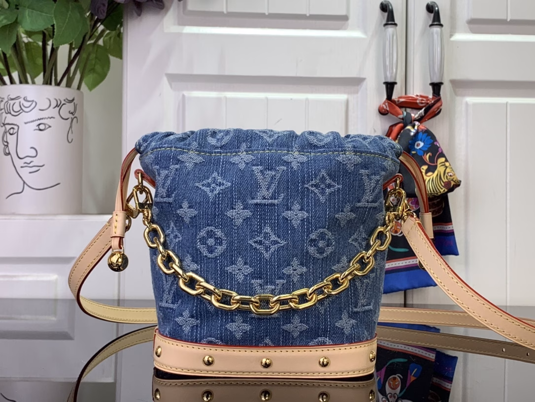 The cotton is rendered in a trendy denim hue and then the classic Monogram pattern is laid out on top, contrasting with the leather trims and dazzling chains. The LV inscription decoration on the drawstring closure adds a playful touch and pays tribute to the brand's long-standing heritage