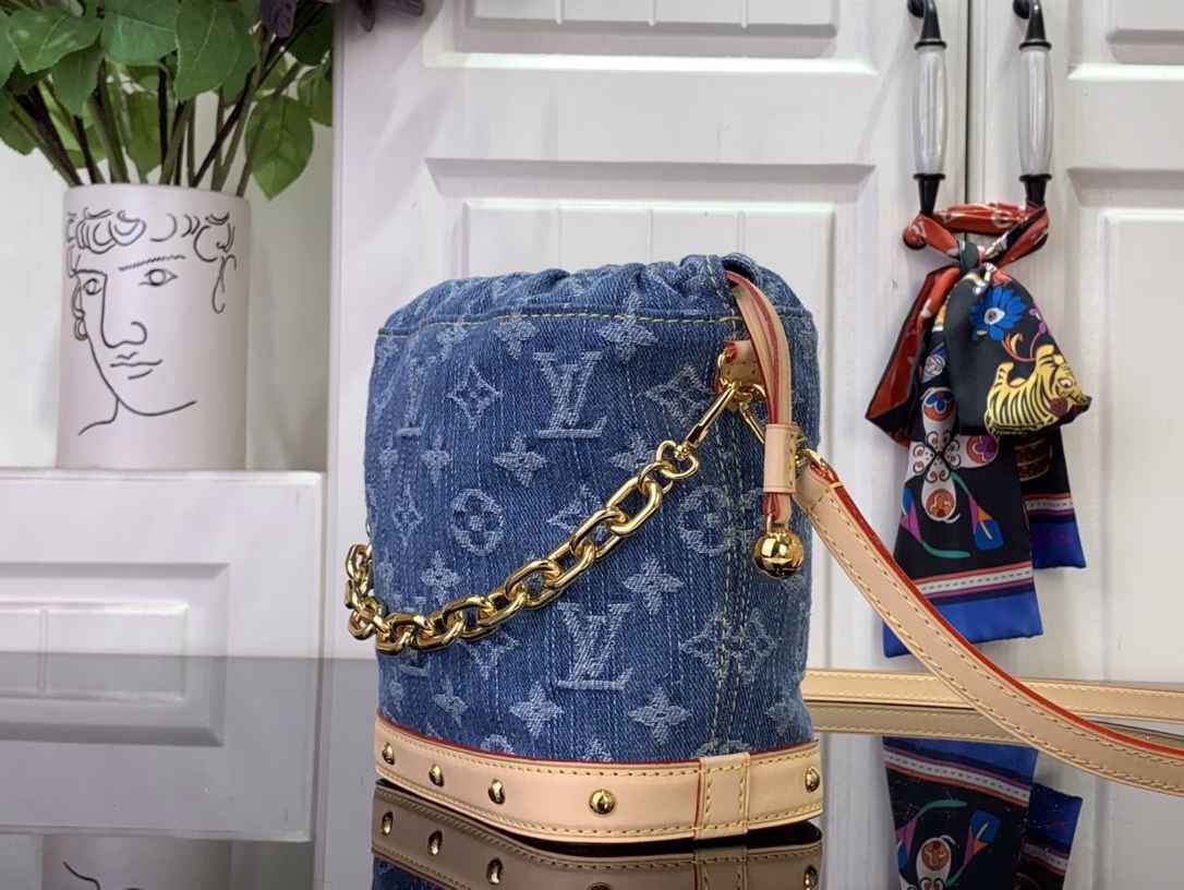 The cotton is rendered in a trendy denim hue and then the classic Monogram pattern is laid out on top, contrasting with the leather trims and dazzling chains. The LV inscription decoration on the drawstring closure adds a playful touch and pays tribute to the brand's long-standing heritage