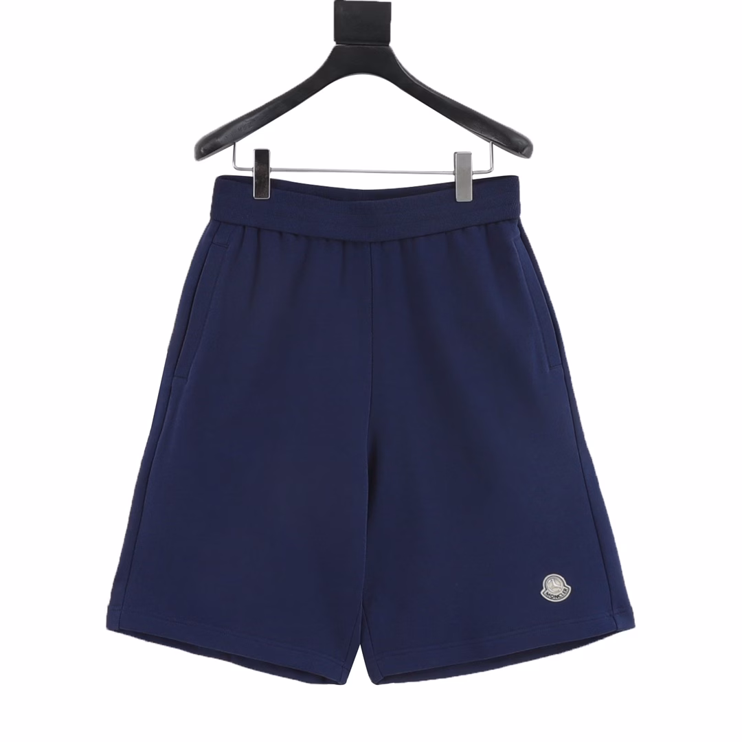 Moncler MC joint large embroidered cotton shortsSingle-sided fish scale fabric woven with cotton as the base, the front is a smooth knitted surface, and the skin-touch surface is formed into a three-dimensional terry loop through the knitting machine's floating thread knitting technology, which increases the fluffiness and delicate touch. The terry loop structure absorbs a lot of water and evaporates quickly, and it is not easy to loosen and deform after multiple washings. The letter LOGO embroidery is formed on the back by the embroidery machine with 16000 needles + 18000 needles. The double-axis linear guide drives the embroidery frame, and the frame moving accuracy can reach 0.01mm/P, ensuring the precise positioning of the embroidery pattern. By actively intervening in the shrinkage potential of cotton fibers, the fabric has achieved a leap from volatile to stable, improving dimensional stability, and is not easy to deform and wrinkle. One-to-one customized joint badges and washing labels