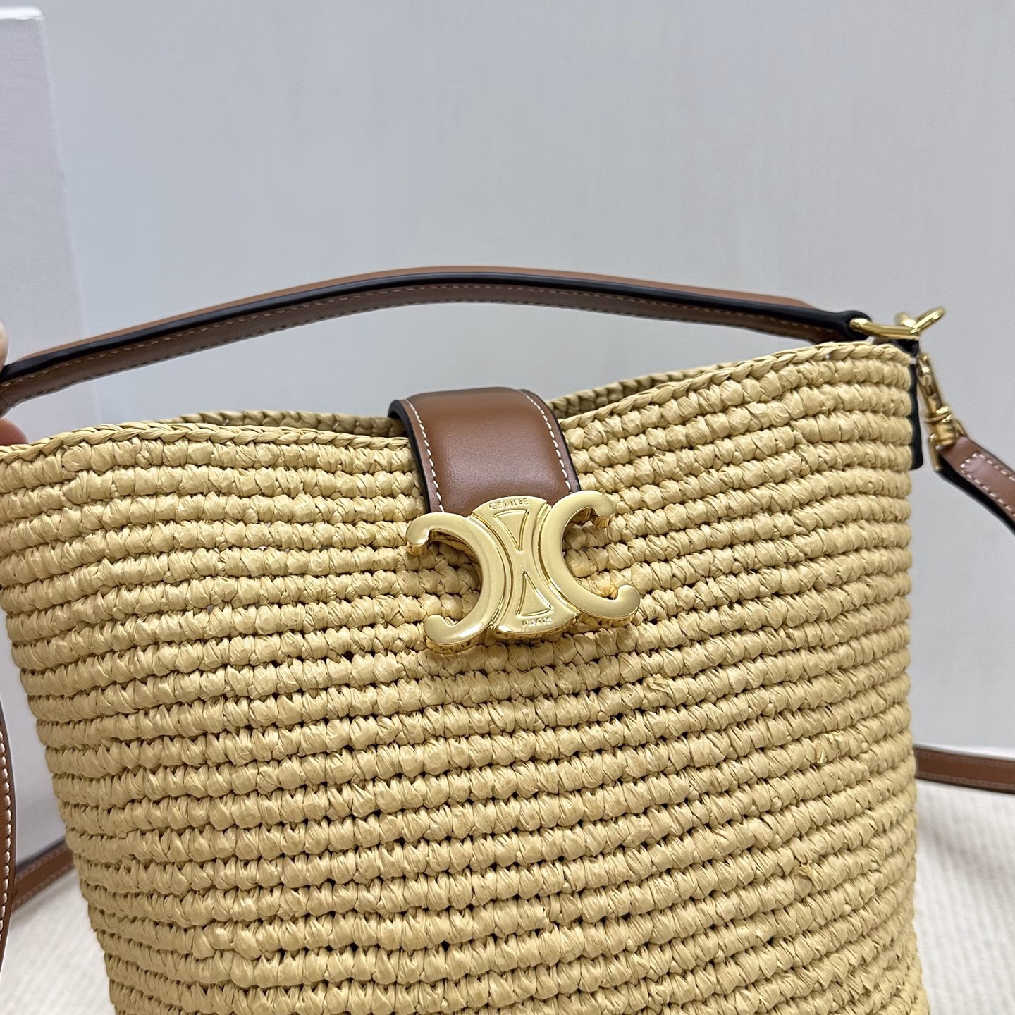 LOUISE Mini Bucket BagMini bag, this model can fit larger smartphones such as PLUSVegetable materialUnlinedGold finishHand, shoulder and crossbodyLeather flap with TRIOMPHE magnetic clasp