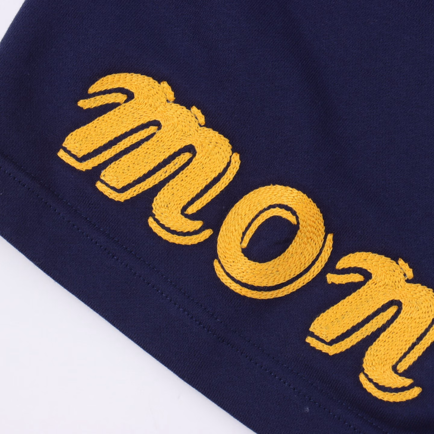 Moncler MC joint large embroidered cotton shortsSingle-sided fish scale fabric woven with cotton as the base, the front is a smooth knitted surface, and the skin-touch surface is formed into a three-dimensional terry loop through the knitting machine's floating thread knitting technology, which increases the fluffiness and delicate touch. The terry loop structure absorbs a lot of water and evaporates quickly, and it is not easy to loosen and deform after multiple washings. The letter LOGO embroidery is formed on the back by the embroidery machine with 16000 needles + 18000 needles. The double-axis linear guide drives the embroidery frame, and the frame moving accuracy can reach 0.01mm/P, ensuring the precise positioning of the embroidery pattern. By actively intervening in the shrinkage potential of cotton fibers, the fabric has achieved a leap from volatile to stable, improving dimensional stability, and is not easy to deform and wrinkle. One-to-one customized joint badges and washing labels