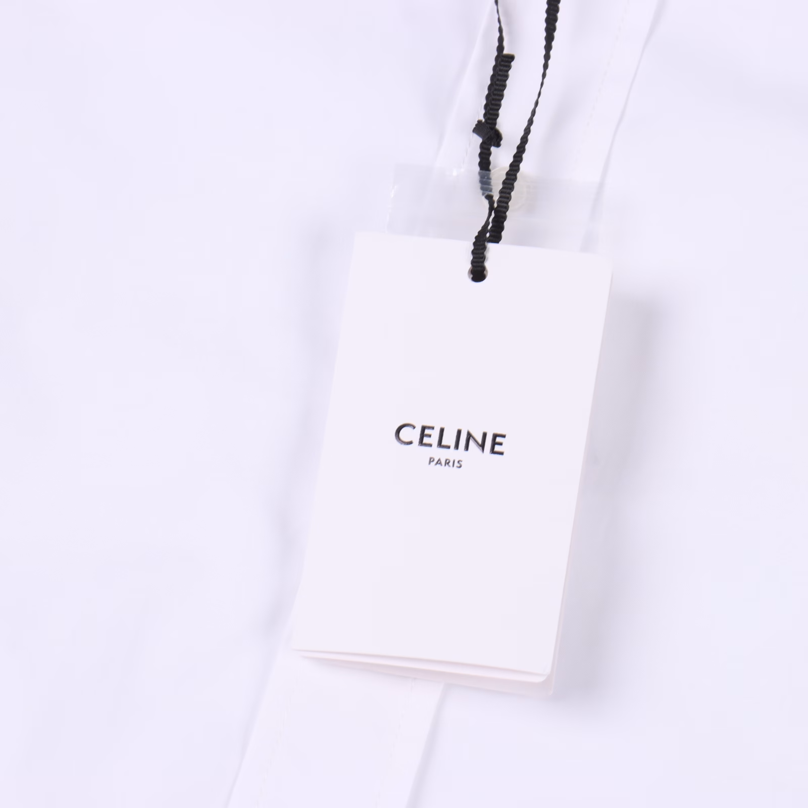 Celine CE long-sleeved shirt with Arc de Triomphe logo embroidery on the hemThe fabric is made of high-count cotton yarn with high warp density and low weft density. The single-color flat embroidery on the front piece is controlled by the high-precision calculation system of the computer embroidery machine to coordinate the machine head, needle bar, and bobbin. The fabric frame moves accurately in the horizontal and vertical directions to form the stitch track, adjust the tension of the upper and lower threads, ensure that the stitches are flat and without floating threads, and form a fine pattern with an error of ±0.1mm. The ironer turns the collar up, irons it from the bottom to the top with high-temperature wet steam, applies pressure to smooth the wrinkles, and then turns it over to the front and repeats the operation. Turn to the neckline to iron out the arc, and press the back collar to the bottom to keep it straight. The shoulder and sleeve part uses the hanging method to avoid pressing the edge. After adjusting the fiber density through the ironer's 