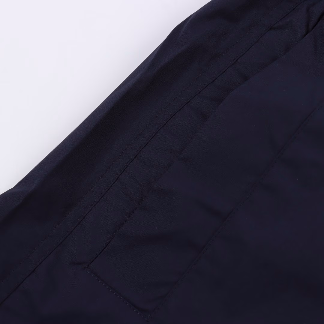 GUC back white label poplin shortsThe cotton fiber is selected to form a plain weave method with twice as many warps as wefts, forming a fine and uniform diamond-shaped particle texture on the surface, smooth to the touch and slightly shiny cotton poplin fabric. Pure cotton material is moisture-absorbent and breathable, and not easy to get stuffy. The high-density structure enhances its wear resistance while also having good wrinkle resistance. The rubber strip is engraved with a high-precision laser beam, and the edge accuracy is ensured to be ±0.1 mm through a dynamic focusing system, thus forming a high-precision letter LOGO. Then use a heat press (temperature controlled at around 150°, pressure 5kg/CM²) to bond the rubber strip to the fabric, and finally carve the same color line at the edge, firmly decorated on the back patch pocket, the elastic waist has built-in elastic silicone tendons to fit different waist shapes, and the outside is equipped with an adjustable drawstring buckle, fixed with a customized buckle head, and the tightness can be fine-tuned with one hand, taking into account both practicality and aesthetics. One-to-one customized drawstring buckle, letter LOGO rubber strip