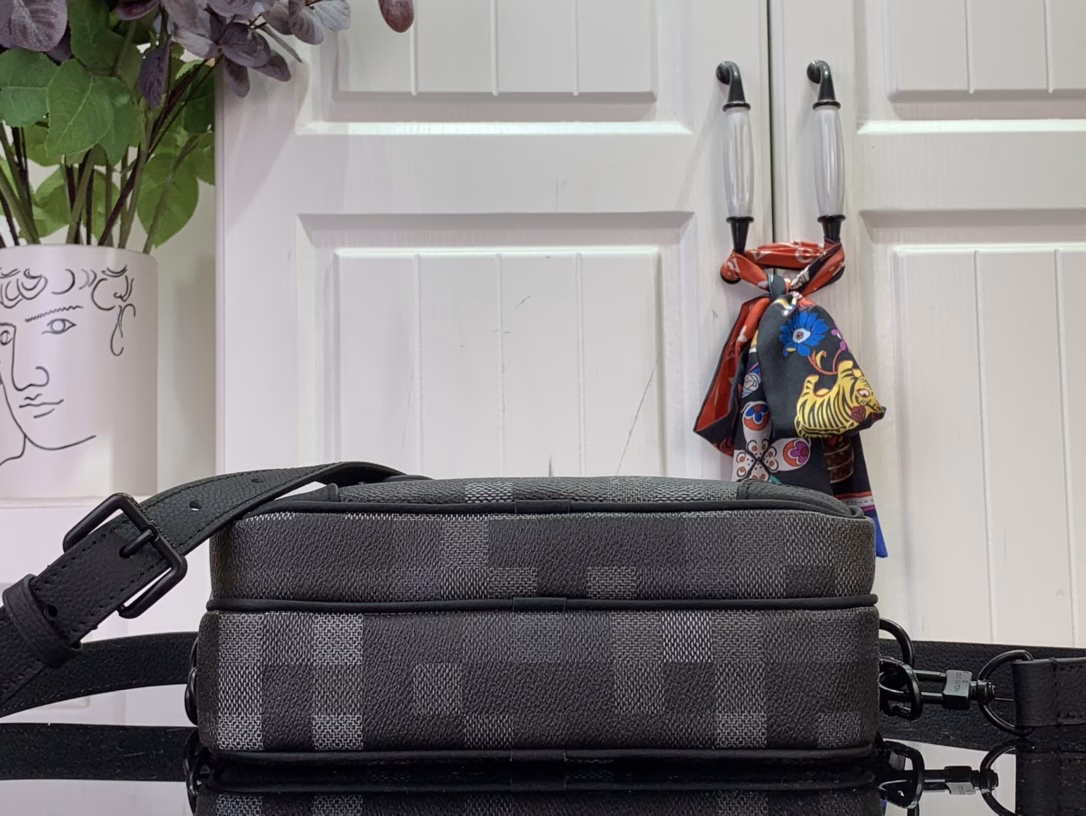 The Nil messenger bag is made from Pharrell Williams's reinterpretation of Damoflage Black coated canvas, combining the designer's fresh perspective with the brand's heritage to create a camouflage-like pixelated Damier pattern. A zip front pocket and main compartment complete the functional configuration.