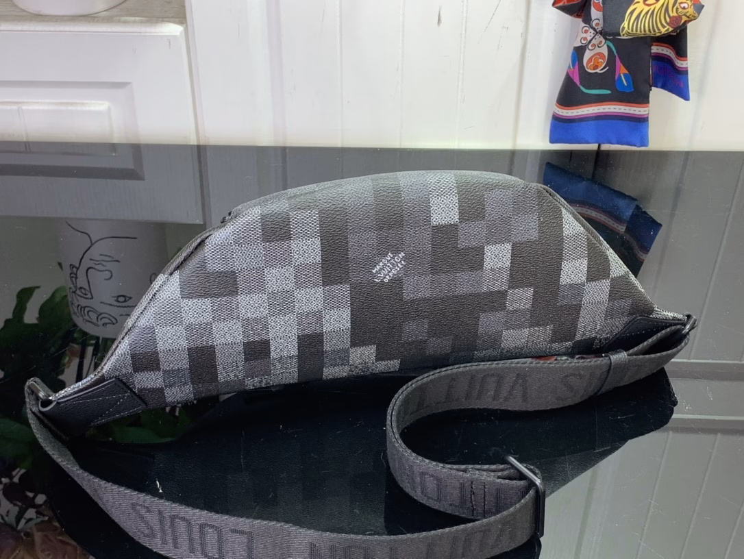 The Rush waist bag is crafted in Damoflage Black canvas with a pixelated Damier graphic overlaid for a camouflage effect. The adjustable strap allows for comfortable waist, shoulder or crossbody wear.