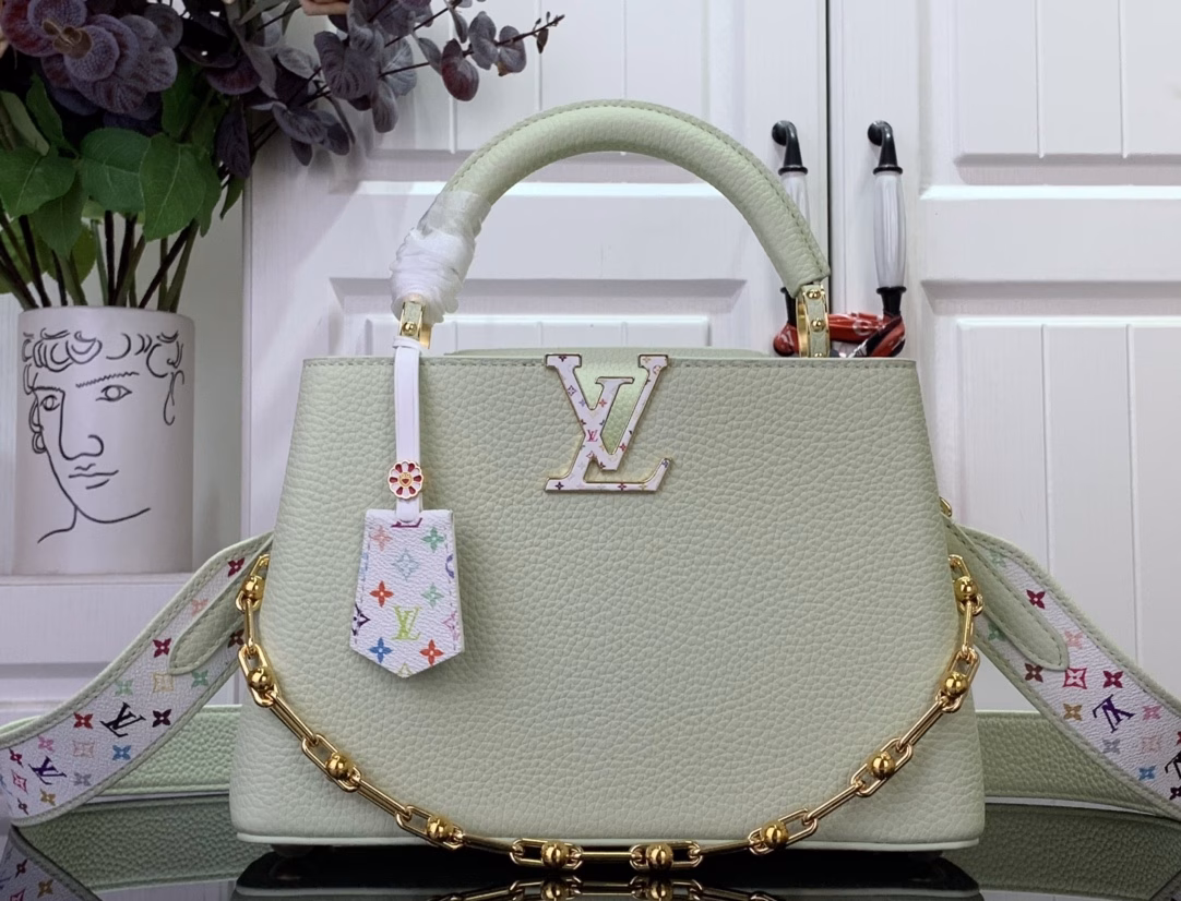 Crafted with playful proportions, the Capucines bag makes a modern statement with a fresh green hue of Taurillon leather, inspired by the rainbow palette of Japanese artist Takashi Murakami. The LV initials, lining, key bell and strap are accented with a joyful and colorful version of the House Monogram pattern, while gleaming gold hardware, including a detachable chain, completes the look with a polished touch.