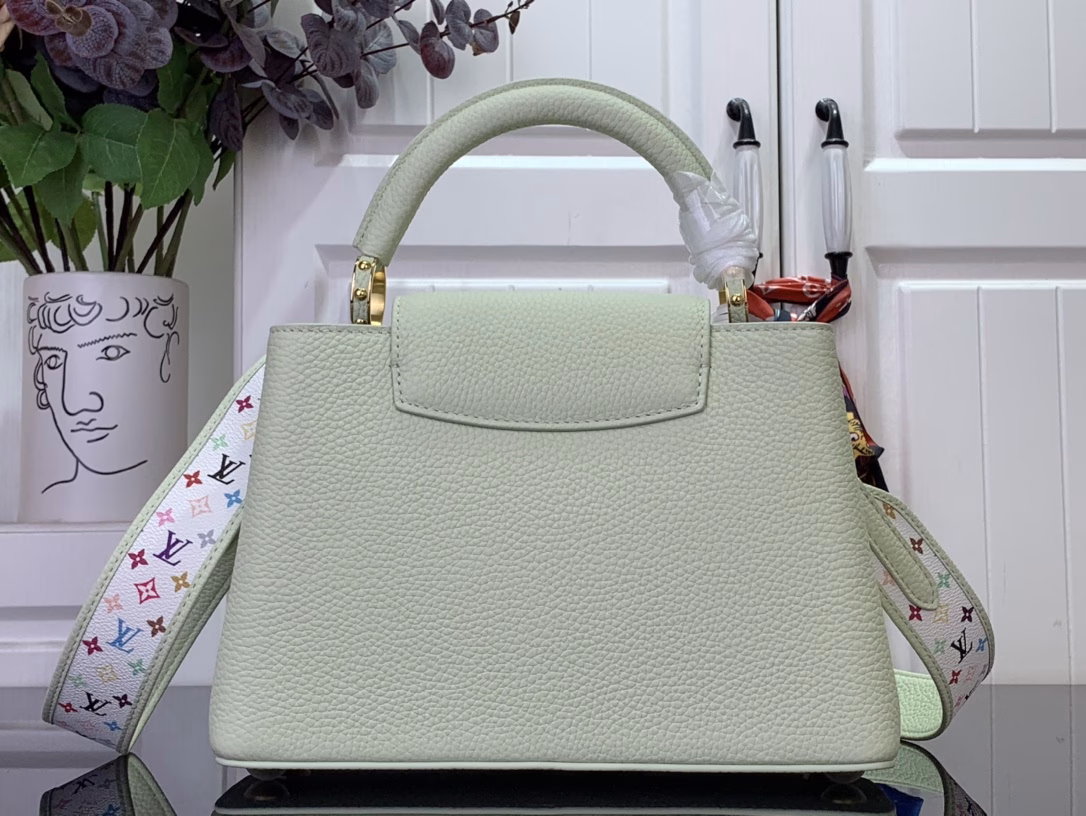 Crafted with playful proportions, the Capucines bag makes a modern statement with a fresh green hue of Taurillon leather, inspired by the rainbow palette of Japanese artist Takashi Murakami. The LV initials, lining, key bell and strap are accented with a joyful and colorful version of the House Monogram pattern, while gleaming gold hardware, including a detachable chain, completes the look with a polished touch.