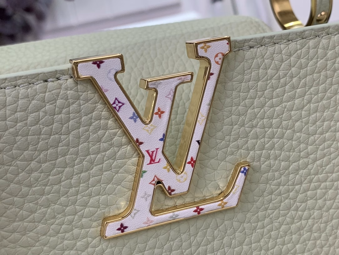 Crafted with playful proportions, the Capucines bag makes a modern statement with a fresh green hue of Taurillon leather, inspired by the rainbow palette of Japanese artist Takashi Murakami. The LV initials, lining, key bell and strap are accented with a joyful and colorful version of the House Monogram pattern, while gleaming gold hardware, including a detachable chain, completes the look with a polished touch.