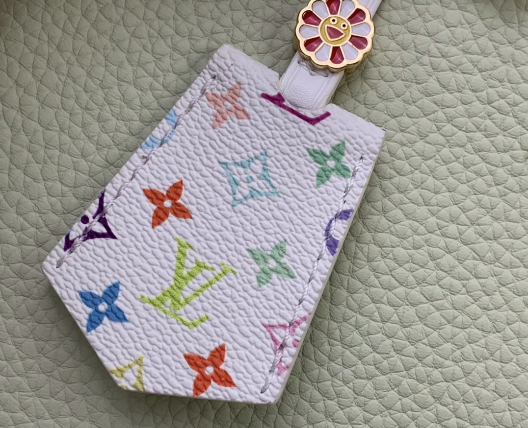 Crafted with playful proportions, the Capucines bag makes a modern statement with a fresh green hue of Taurillon leather, inspired by the rainbow palette of Japanese artist Takashi Murakami. The LV initials, lining, key bell and strap are accented with a joyful and colorful version of the House Monogram pattern, while gleaming gold hardware, including a detachable chain, completes the look with a polished touch.