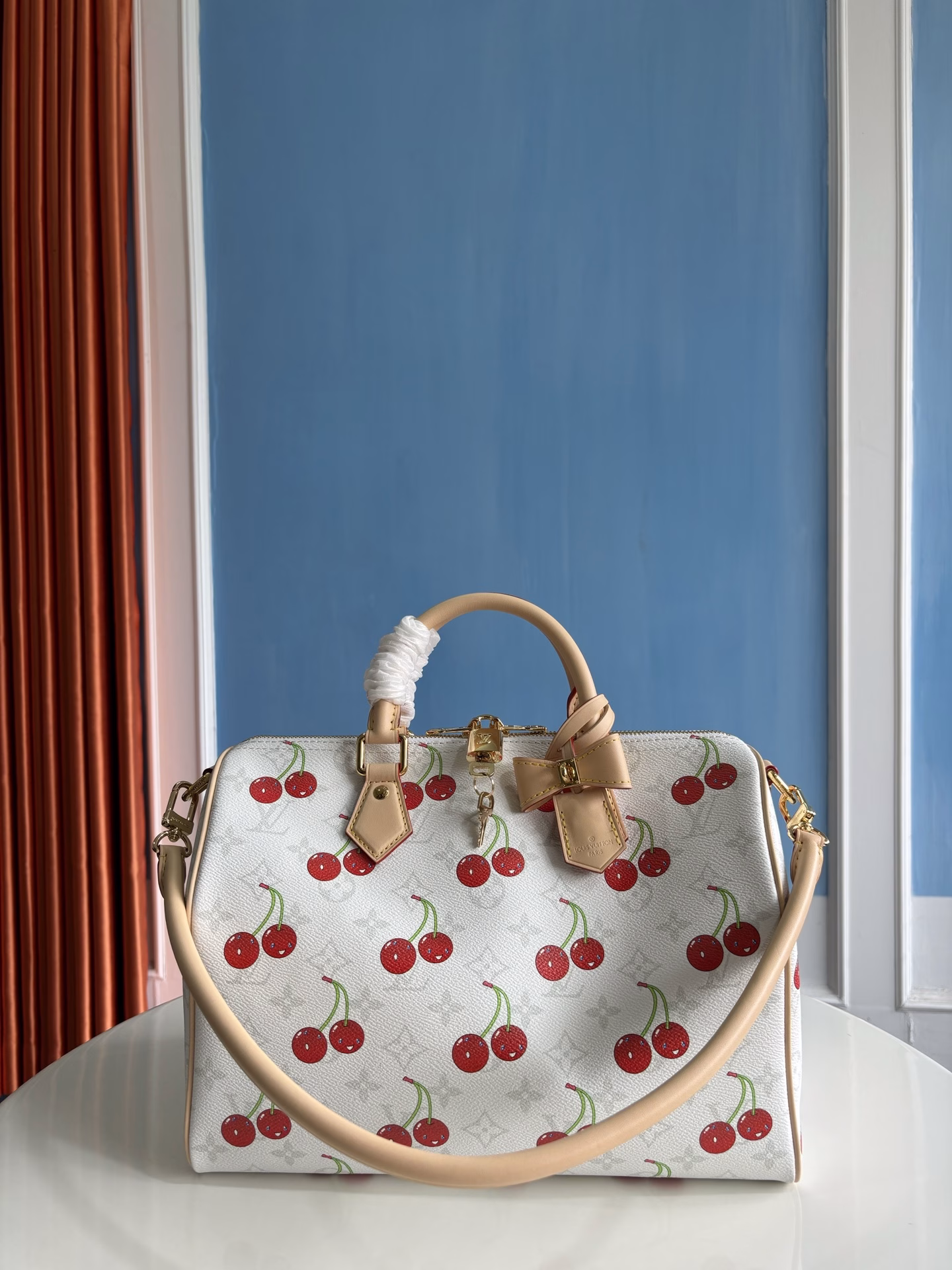 The Speedy Soft 30 bag is inspired by the Louis Vuitton x Takashi Murakami remake. The Monogram coated canvas is presented in a muted color palette to highlight the vibrant cherry pattern created by the Japanese artist. The denim interior, the Toron top handle and detachable Toron shoulder strap are made from leather, and the bow-shaped key holder is a rich detail.