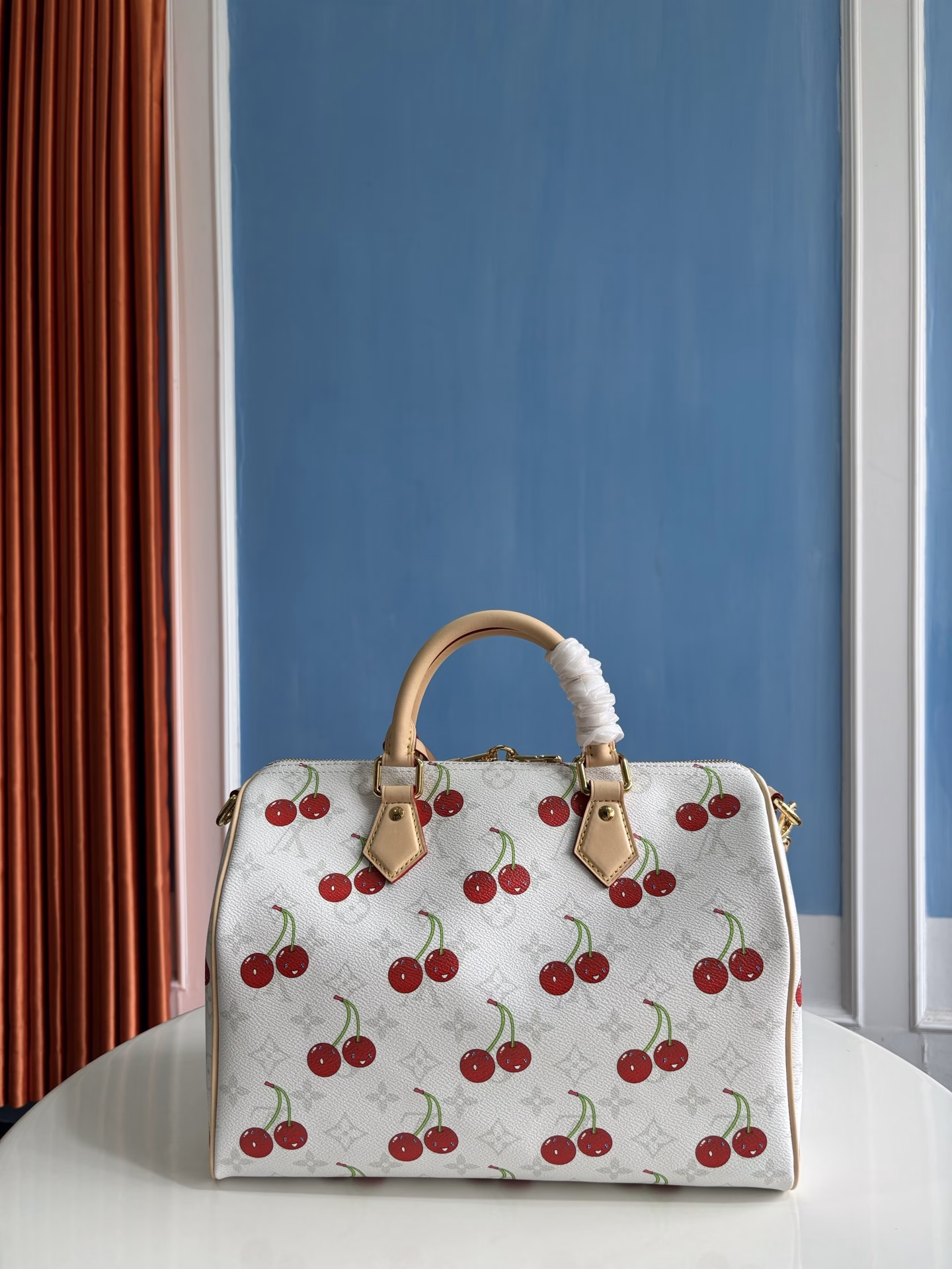 The Speedy Soft 30 bag is inspired by the Louis Vuitton x Takashi Murakami remake. The Monogram coated canvas is presented in a muted color palette to highlight the vibrant cherry pattern created by the Japanese artist. The denim interior, the Toron top handle and detachable Toron shoulder strap are made from leather, and the bow-shaped key holder is a rich detail.