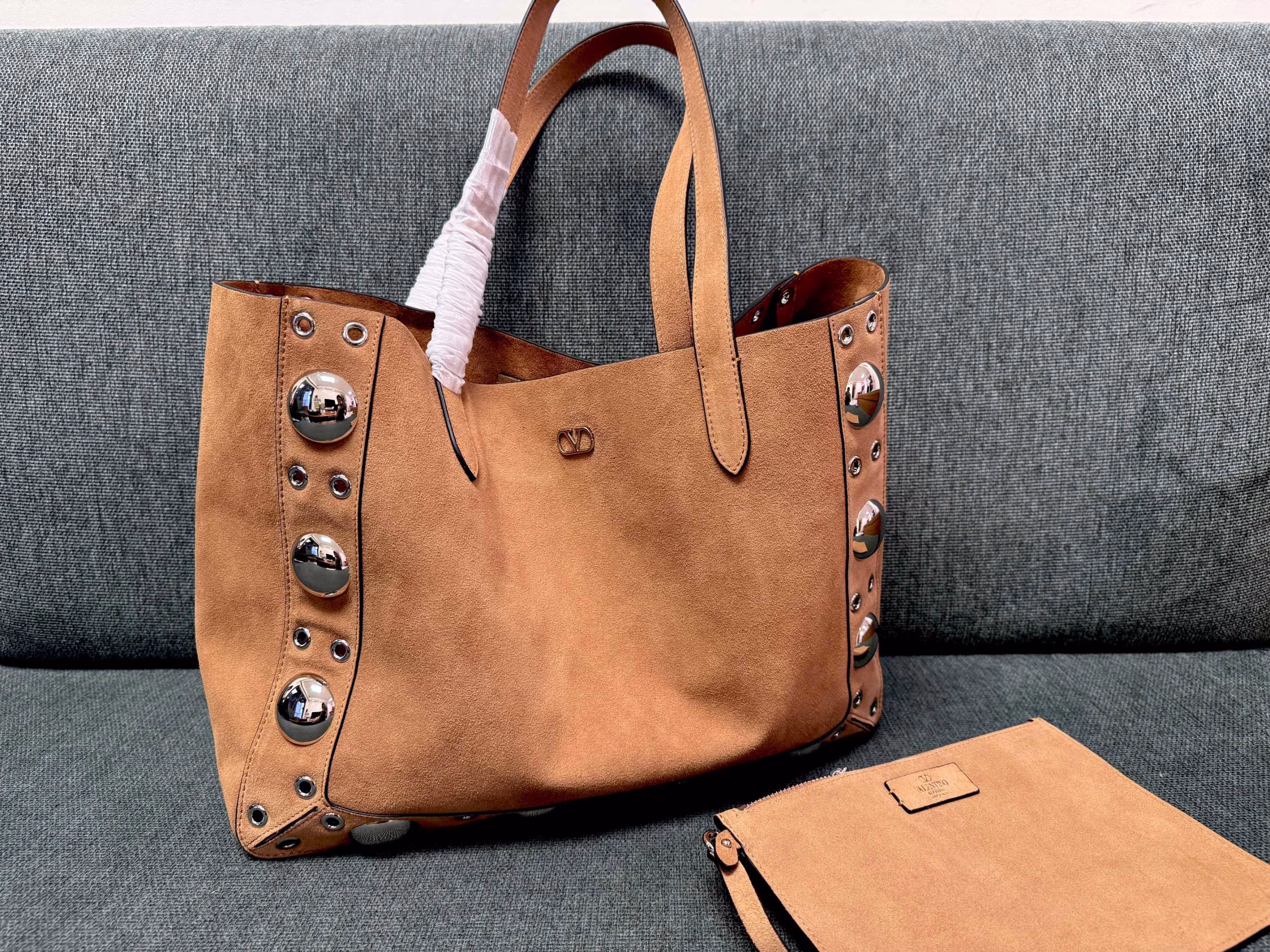 VALENTINO 🍃 GARAVANI NELLCOTEMedium-sized tote bag, decorated with spherical rivets and circular hollowed-out decorations. This bag can be carried by hand or comfortably on the shoulder through the handle.Palladium-plated metal accessories