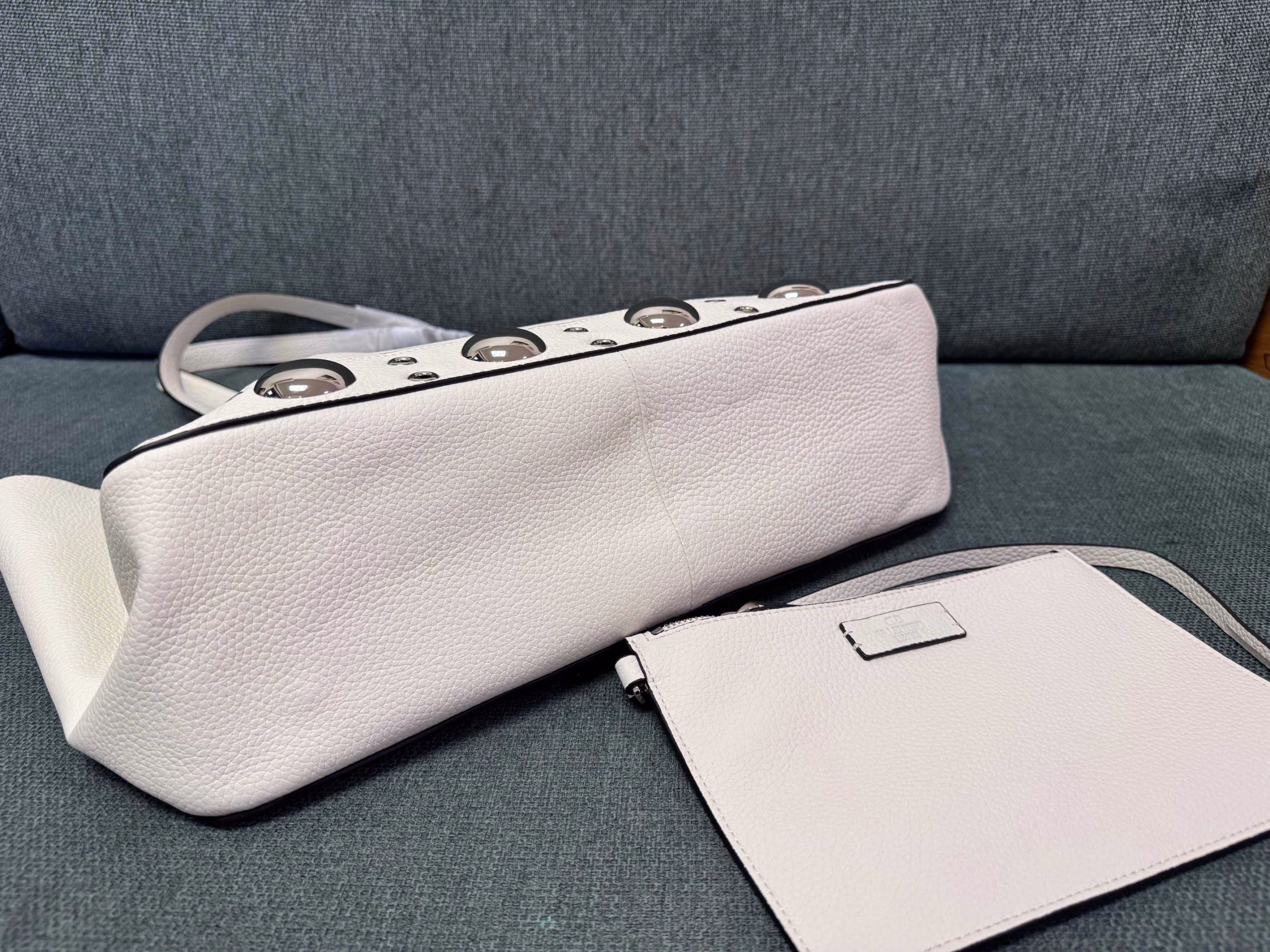 VALENTINO 🍃 GARAVANI NELLCOTEMedium-sized tote bag, decorated with spherical rivets and circular hollowed-out decorations. This bag can be carried by hand or comfortably on the shoulder through the handle.Palladium-plated metal accessories