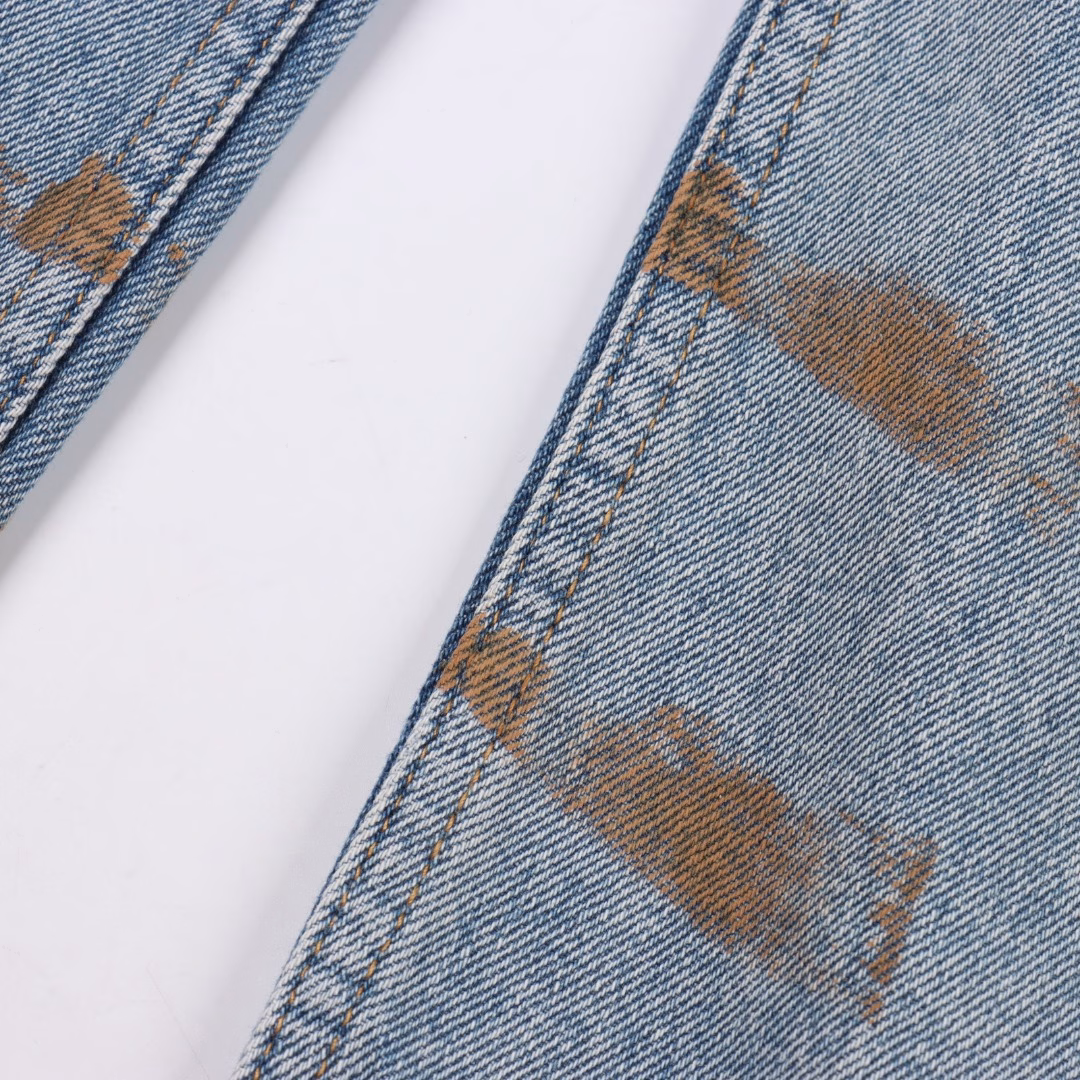 Balenciaga 25ss BAGGA wide-leg denim trousersIt is made of high-density cotton denim fabric and processed through a special blending technique, incorporating a trace amount of elastic fibers to enhance wearing comfort. The fabric undergoes multiple stages of water washing treatment, including enzyme washing, stone grinding and hand brushing, to create a natural fading effect and present a retro and aged texture. The yarn is spun by ring spinning technology to enhance the fabric's toughness and texture layering, ensuring a balance between stiffness and softness. Based on the classic straight-leg style, the leg lines are optimized through precise three-dimensional cutting. The front and rear pieces are spliced with a slight taper, ensuring a drape while avoiding bulkiness. The waistband design of the trousers may incorporate hidden adjustment loops, balancing a good fit and minimalist aesthetics. The buttons are made of specially crafted alloy and have undergone an aged coating treatment, engraved with the brand's signature LOGO. The rivets and zippers are made of the same series of metals and have passed salt spray tests to ensure oxidation resistance. At the same time, they maintain a rough industrial style, echoing the overall retro tone. Through the integration of deconstructionism and street style, the craftsmanship details are transformed into visual language - such as deliberately retained unfinished rough edges and asymmetrical dyeing, etc., strengthening the brand's rebellious spirit while maintaining the practicality of high-end items