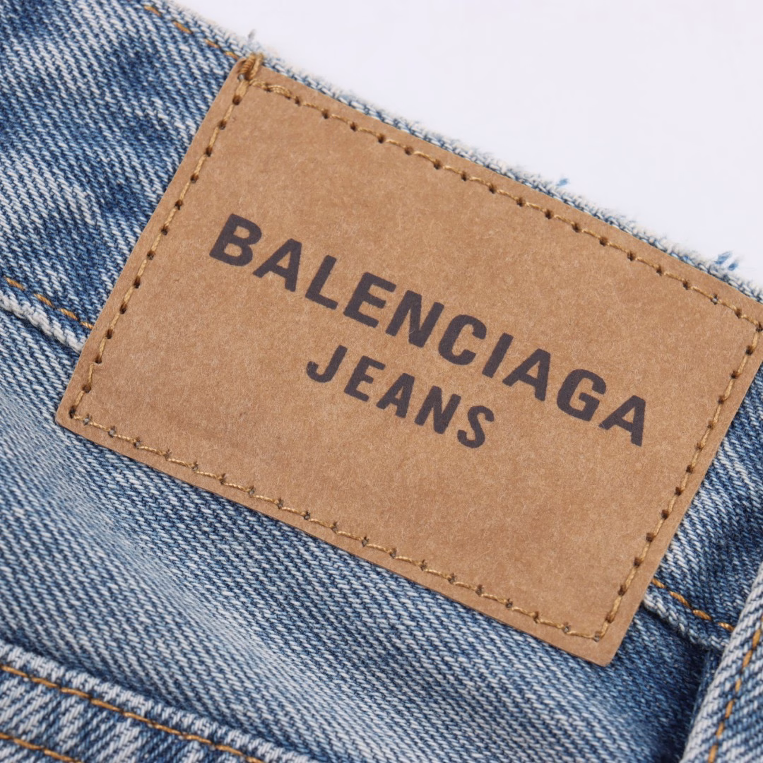 Balenciaga 25ss BAGGA wide-leg denim trousersIt is made of high-density cotton denim fabric and processed through a special blending technique, incorporating a trace amount of elastic fibers to enhance wearing comfort. The fabric undergoes multiple stages of water washing treatment, including enzyme washing, stone grinding and hand brushing, to create a natural fading effect and present a retro and aged texture. The yarn is spun by ring spinning technology to enhance the fabric's toughness and texture layering, ensuring a balance between stiffness and softness. Based on the classic straight-leg style, the leg lines are optimized through precise three-dimensional cutting. The front and rear pieces are spliced with a slight taper, ensuring a drape while avoiding bulkiness. The waistband design of the trousers may incorporate hidden adjustment loops, balancing a good fit and minimalist aesthetics. The buttons are made of specially crafted alloy and have undergone an aged coating treatment, engraved with the brand's signature LOGO. The rivets and zippers are made of the same series of metals and have passed salt spray tests to ensure oxidation resistance. At the same time, they maintain a rough industrial style, echoing the overall retro tone. Through the integration of deconstructionism and street style, the craftsmanship details are transformed into visual language - such as deliberately retained unfinished rough edges and asymmetrical dyeing, etc., strengthening the brand's rebellious spirit while maintaining the practicality of high-end items