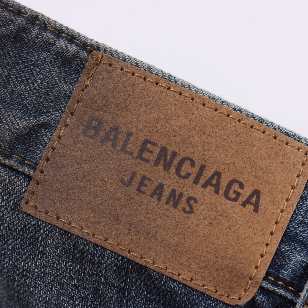 Balenciaga 25ss show low-rise denim trousersIt is made of high-density cotton denim fabric and processed through a special blending technique, incorporating a trace amount of elastic fibers to enhance wearing comfort. The fabric undergoes multiple stages of water washing treatment, including enzyme washing, stone grinding and hand brushing, to create a natural fading effect and present a retro and aged texture. The yarn is spun by ring spinning technology to enhance the fabric's toughness and texture layering, ensuring a balance between stiffness and softness. Based on the classic straight-leg style, the leg line is optimized through precise three-dimensional cutting. The front and back pieces are slightly conical spliced to ensure a drape while avoiding bulkiness. The waistband design may incorporate hidden adjustment loops to balance fit and minimalist aesthetics. The buttons are made of specially designed alloy materials. The surface has undergone an aged coating treatment, engraved with the brand's signature LOG. The rivets and zippers are made of the same series of metals and have passed salt spray tests to ensure oxidation resistance. At the same time, it maintains a rough industrial style, echoing the overall retro tone. Through the integration of deconstructionism and street style, the craftsmanship details are transformed into visual language - such as deliberately retained unfinished burrs, asymmetrical dyeing, etc. Strengthen the brand's rebellious spirit while maintaining the practicality of high-end items