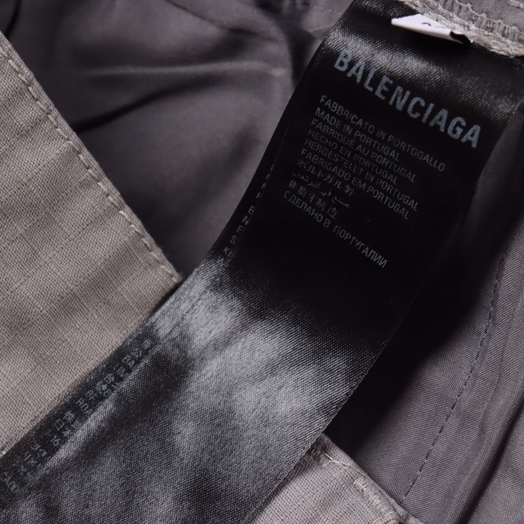 Balenciaga 25ss Loop distressed work shortsThe workwear pants are reconfigured with advanced customization techniques to achieve functional design. The main body is made of high-count, high-density checkered woven fabric, which undergoes multiple washing processes to present an aged texture. It is then superimposed with a spray-painted fastener process, a high-precision sandblasting + enzyme washing technology, to create a three-dimensional aged effect. The deliberate aging creates natural wrinkles and fading effects. All hardware parts are custom-made by brand molds. The zipper teeth and pull straps are electroplated with zinc alloy. It is engraved with the exclusive 