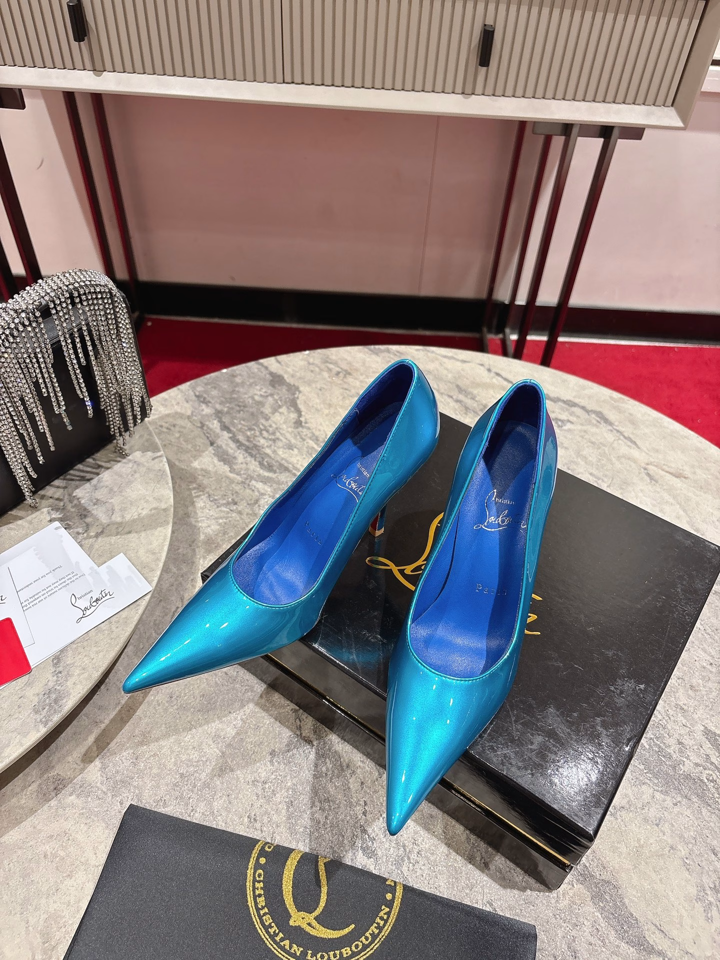 This pair of shoes features a 100mm high heel, revealing the iconic Loubi red sole, and is equipped with soft insoles made of black glossy calfskin. This shoe features a new 