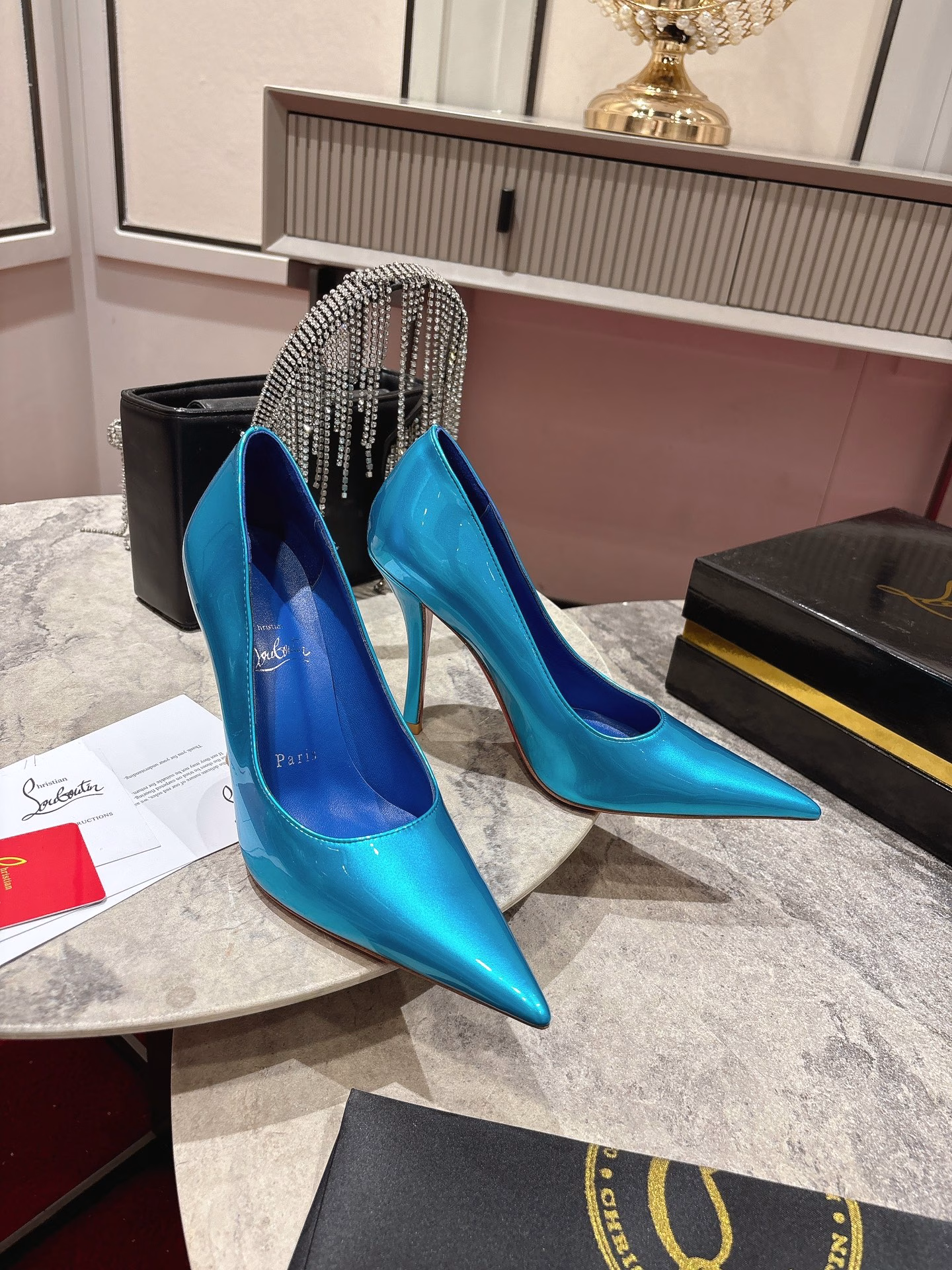 This pair of shoes features a 100mm high heel, revealing the iconic Loubi red sole, and is equipped with soft insoles made of black glossy calfskin. This shoe features a new 