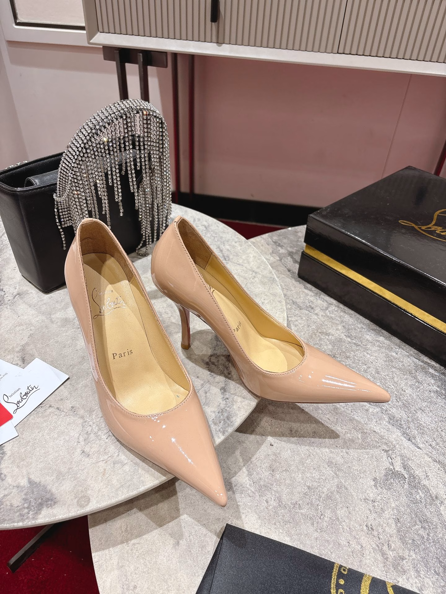 This pair of shoes features a 100mm high heel, revealing the iconic Loubi red sole, and is equipped with soft insoles made of black glossy calfskin. This shoe features a new 