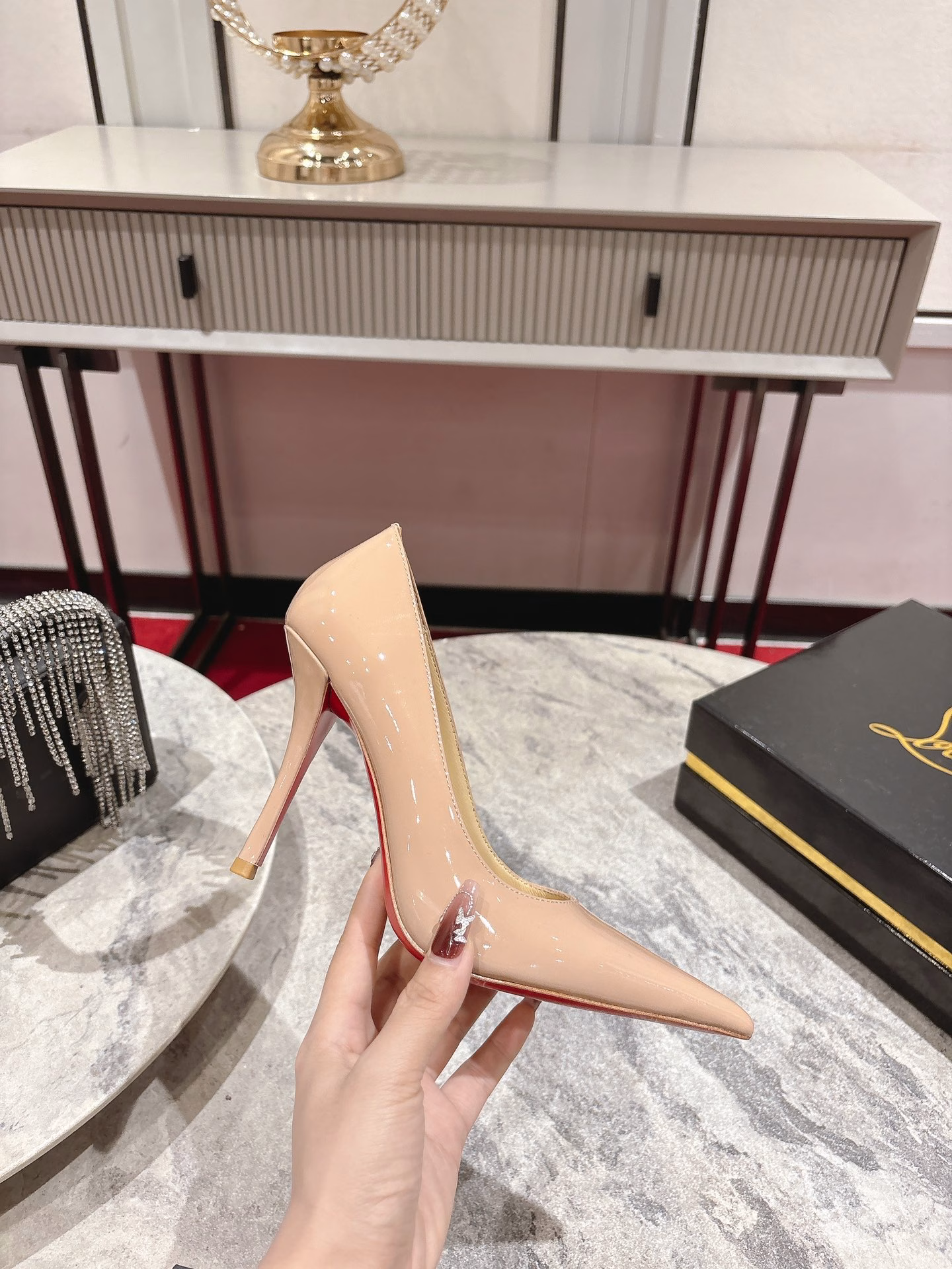 This pair of shoes features a 100mm high heel, revealing the iconic Loubi red sole, and is equipped with soft insoles made of black glossy calfskin. This shoe features a new 