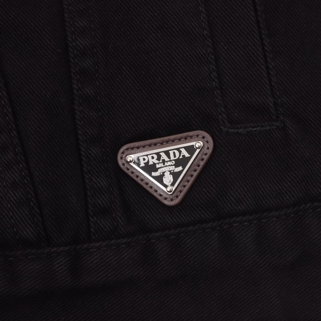 Prada PRD denim jacket with triangular logo on the hemCustom-made high-density Phantom twill satin with fine velvet, equipped with an imported infrared positioning machine for more precise positioning, is firm and sturdy. The first step is to position the spray horse fastener and then create a gradient effect by hand rubbing. Use a spray gun to precisely spray the reagent solution onto the designated position on the shirt according to the design requirements, allowing the reagent to undergo a chemical reaction with the fabric to form a gradual gradient effect. Finally, water boiling is used to reinforce the color. Follow the original color series to do the Biwen dyeing color matching. First, based on the original color and fabric material, select the specially made Biwen dyeing dye, then heat it to the appropriate temperature for immersion dyeing treatment. Finally, carry out the color matching implementation, customize the auxiliary materials, and create a fitted pattern