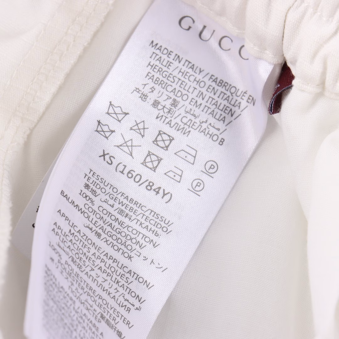 Gucci's white casual sports shorts with red and green letter prints on the backYB purchased a pattern, made of custom cotton fabric, which is comfortable, soft, skin-friendly and breathable. The front has a slanted pocket and a large flip pocket. The design is simple, with elastic bands for the waist circumference. The white drawstring is paired with engraved hardware. The back is covered with fabric pocket details, decorated with red and green stripe prints and brand letters. It can be matched with various types of clothing to create a fashionable look. Custom accessories are available. All three labels are complete. It is suitable for both men and women!
