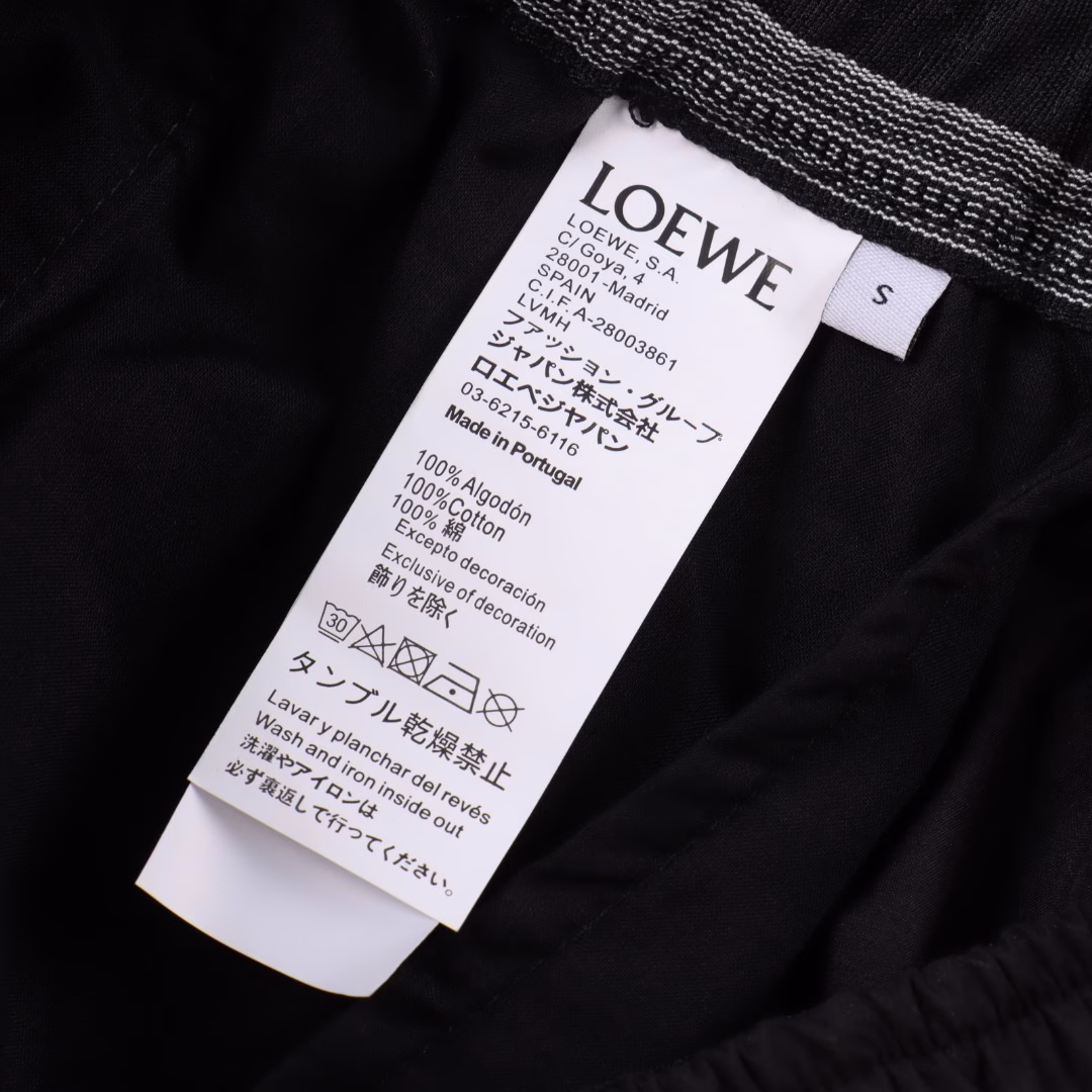 Loewe Back Pocket Hollow Embroidery ShortsMade of 32% nylon and 68% cotton blend. The hydrophobic fibers of nylon form microchannels to accelerate moisture discharge, with a moisture permeability of 4500g/m² for 24 hours, and the tear strength of nylon fibers reaches 45N, making the fabric have good wear resistance. The CAD plate making system is used to preset the solid embroidery area and the hollow area, and a high-precision Anagram embroidery of 35 needles/cm² is formed through a multi-head embroidery machine with a needle speed of 1000rpm. Then use the laser cutting process to accurately remove the base fabric in the embroidery hollow area to form a geometric hole shape. The laser accuracy of ±0.1mm makes the hollow part smooth and without burrs. The overall line is straight and delicate, the fabric is comfortable and soft, and the color is consistent without color difference. It can be matched with the same style to create a fashionable look, suitable for various occasions, customized accessories, three standards are complete, and the same style for men and women