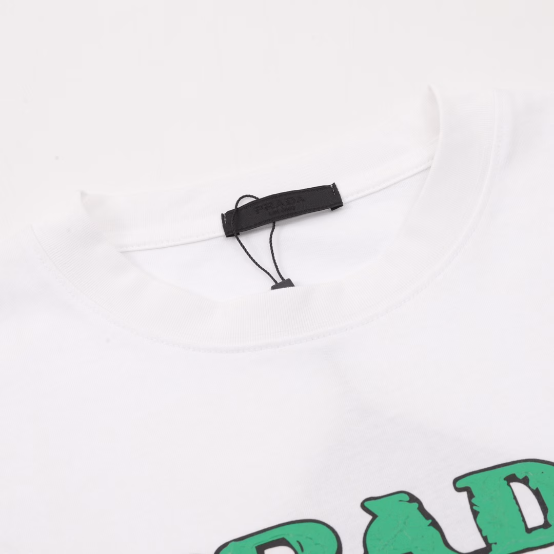 Prada 25ss green letter logo printed short sleevesThe classic triangle logo is displayed with graffiti on the chestUsing 260g cotton fabric and 40-count double yarn fabric, it has high textile density, good drape and is not easy to deform.The thick texture and compact spinning process will not affect the breathability of the Tee. The color saturation is very high, and the colorful foaming printing process makes the pattern more textured. The same style for men and women, recommended for summer street wear